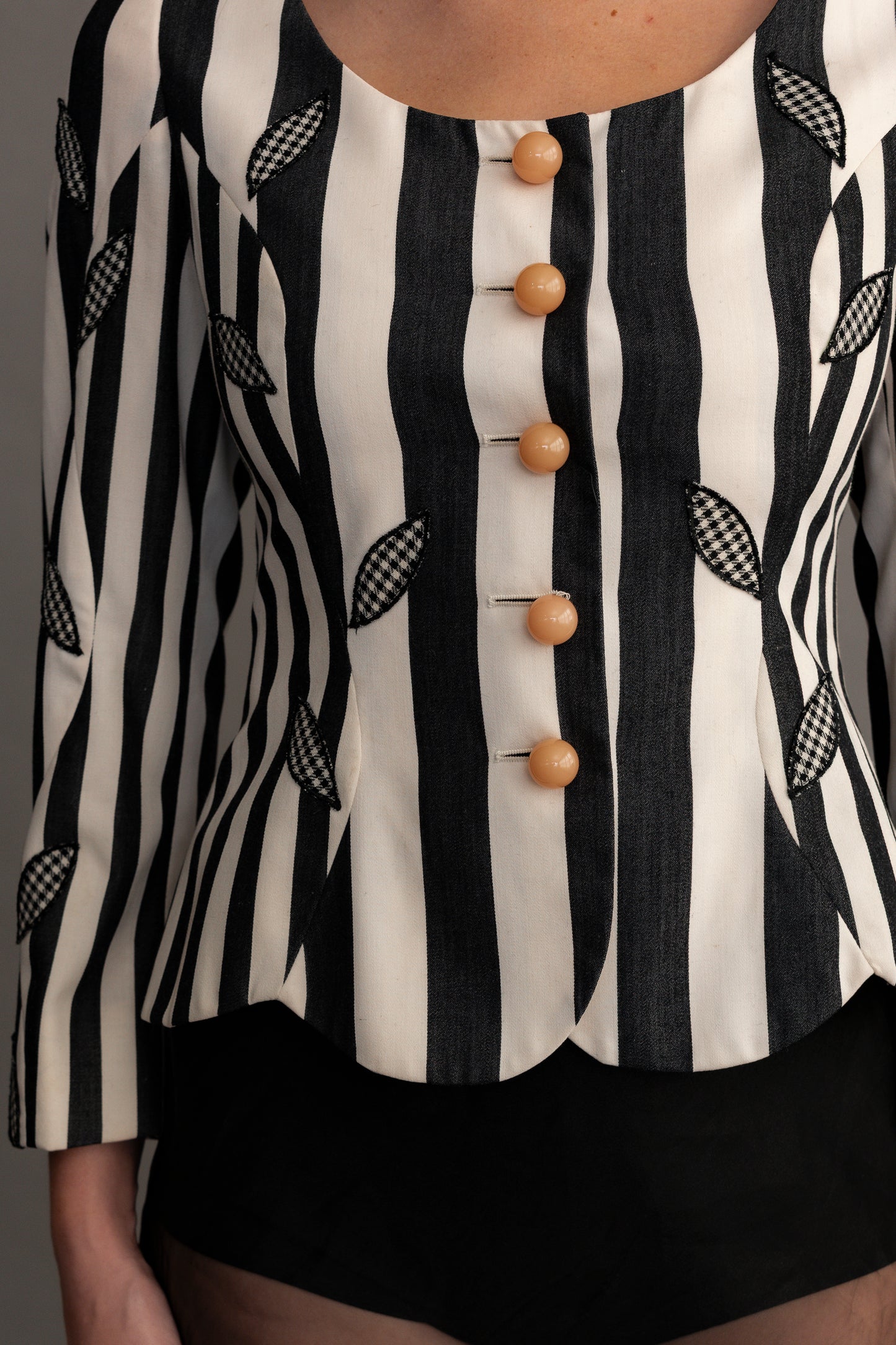 Black and white striped blouse with wooden buttons on a plain background