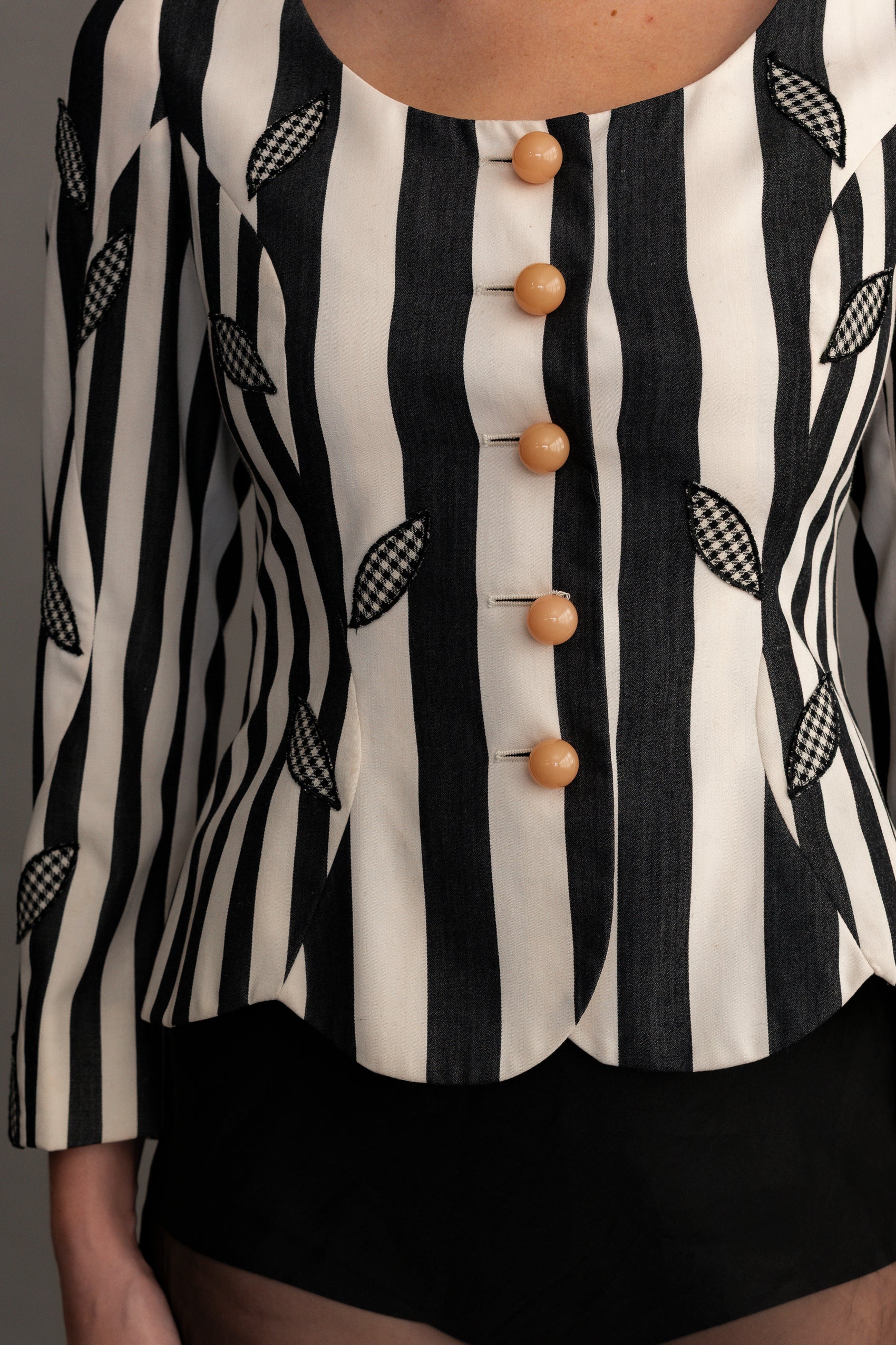 Black and white striped blouse with wooden buttons on a plain background